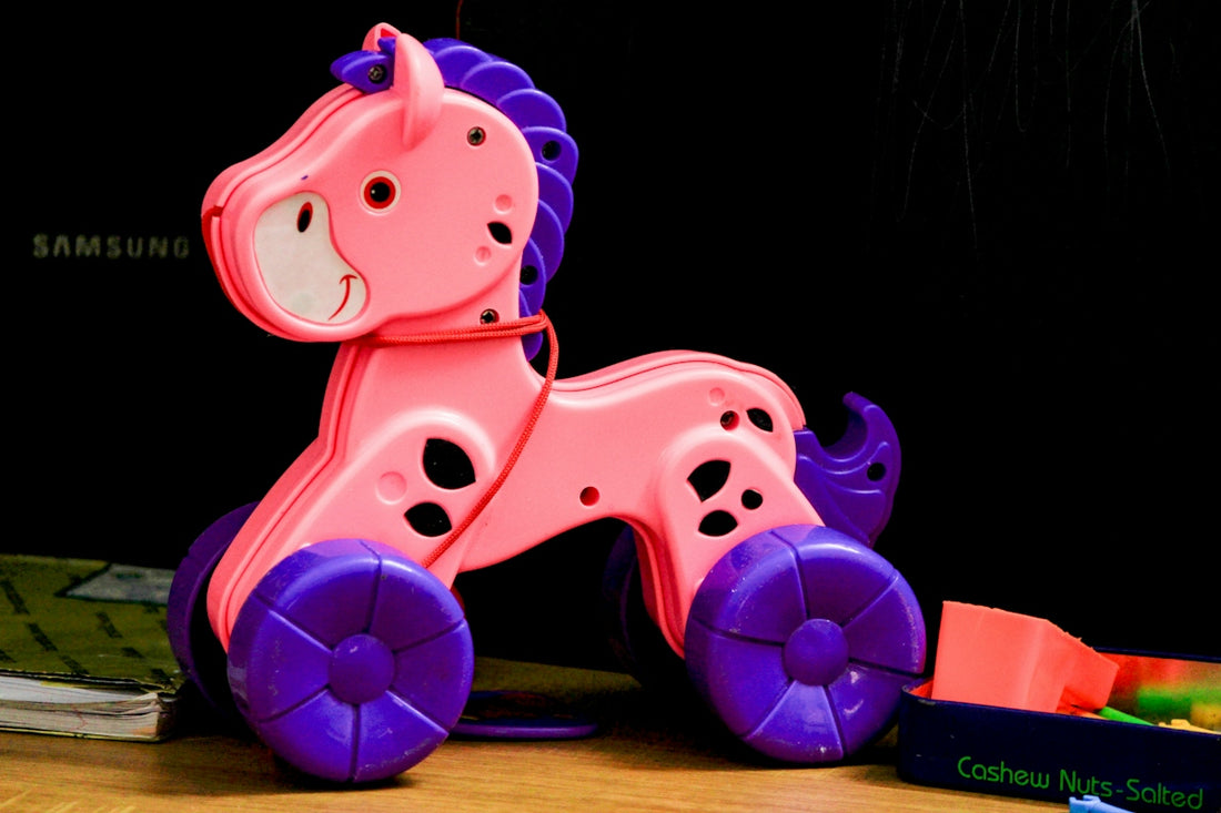 A pink toy horse with purple wheels on a table